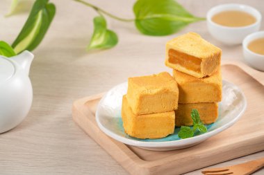 Lezzetli Tayvan usulü ananaslı pasta. Tahta bir masada tatlı. Arka planda sıcak çay var..