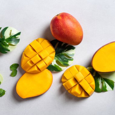 Mango arka plan tasarımı konsepti. Gri masa yaprakları ile kesilmiş taze mango desenli üst manzara.