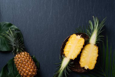 Koyu mavi arka planda tropikal yapraklı taze kesilmiş ananas manzarası.