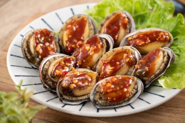 Baharatlı domates soslu leziz istiridye, ahşap masa arkasında Tayvan beş aromalı sos..