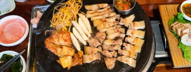 Jeju Kore restoranında kızarmış siyah domuz eti, demir tabakta taze Kore mutfağı marul, kimchi, banchan ve sos, yaşam tarzı.
