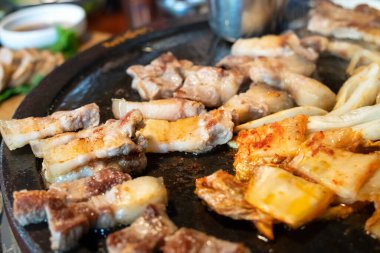 Jeju Kore restoranında kızarmış siyah domuz eti, demir tabakta taze Kore mutfağı marul, kimchi, banchan ve sos, yaşam tarzı.