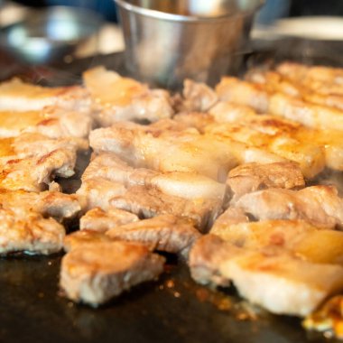 Jeju Kore restoranında kızarmış siyah domuz eti, demir tabakta taze Kore mutfağı marul, kimchi, banchan ve sos, yaşam tarzı.