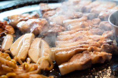 Jeju Kore restoranında kızarmış siyah domuz eti, demir tabakta taze Kore mutfağı marul, kimchi, banchan ve sos, yaşam tarzı.