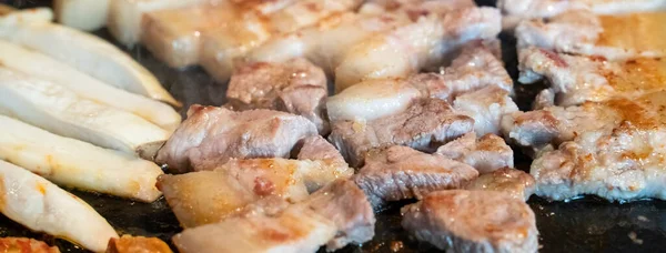 Jeju Kore restoranında kızarmış siyah domuz eti, demir tabakta taze Kore mutfağı marul, kimchi, banchan ve sos, yaşam tarzı.