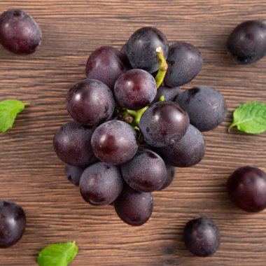 Lezzetli bir demet mor üzüm meyvesi ahşap masa arkasına dökülmüş..