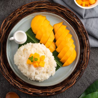 Lezzetli Tayland mangolu yapışkan pirinç ve gri masa arkasındaki tabakta taze mango meyvesi..