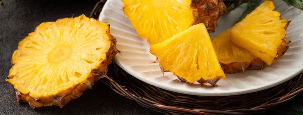 新鲜切碎的多汁菠萝片放在深灰色桌子背景的盘子里 — 图库照片