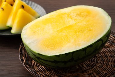 Sliced yellow golden watermelon in a plate on wooden table background ready for eating.