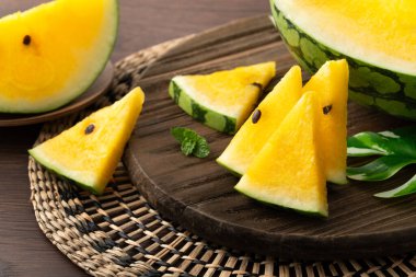 Sliced yellow golden watermelon in a plate on wooden table background ready for eating.