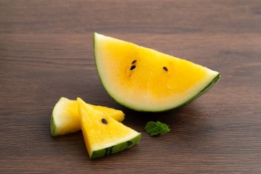 Sliced yellow golden watermelon in a plate on wooden table background ready for eating.