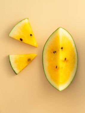 Sliced yellow golden watermelon pattern flat lay on pastel yellow table background.