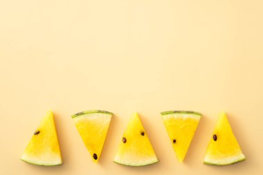 Sliced yellow golden watermelon pattern flat lay on pastel yellow table background.