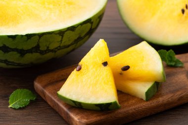 Sliced yellow golden watermelon in a plate on wooden table background ready for eating.