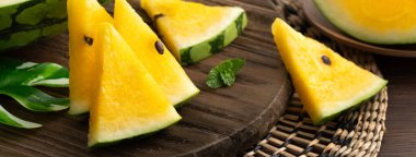 Sliced yellow golden watermelon in a plate on wooden table background ready for eating.