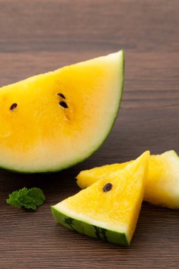 Sliced yellow golden watermelon in a plate on wooden table background ready for eating.