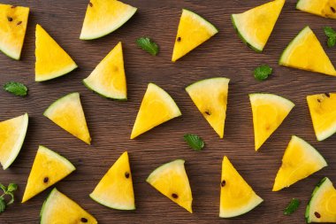 Dilimlenmiş sarı karpuz desenli düz tahta masa arkasında yatıyordu..