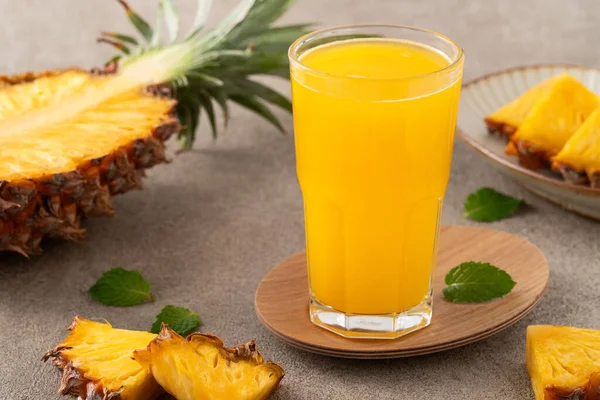 stock image Fresh delicious pineapple juice smoothie, cold drink in glass cup on gray table background.