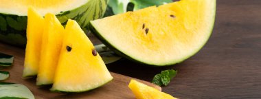 Sliced yellow golden watermelon in a plate on wooden table background ready for eating.