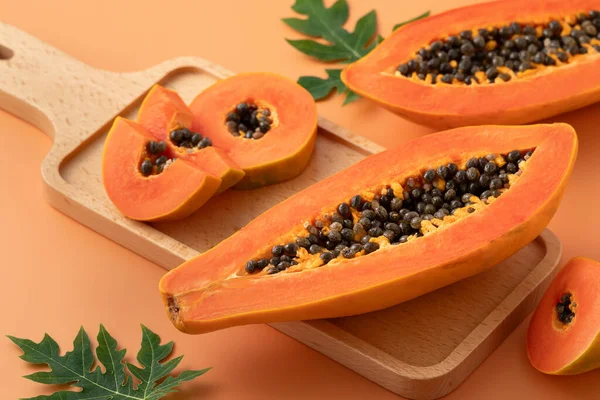 Tropikal gurme tasarım konsepti için turuncu masa zemininde taze kesilmiş papaya meyvesi..