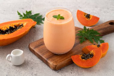 Tropikal meyve tasarımı konsepti için gri masa zemininde cam bardakta taze, lezzetli papaya sütü..