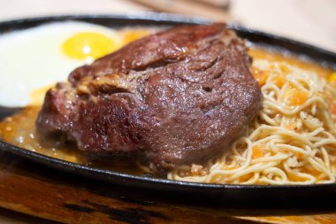 Tayvan usulü özel cızırtılı biftek, erişte, yumurta ve sos geleneksel gece pazarında sıcak demir bir tahtanın üzerinde..