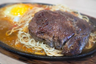 Tayvan usulü özel cızırtılı biftek, erişte, yumurta ve sos geleneksel gece pazarında sıcak demir bir tahtanın üzerinde..