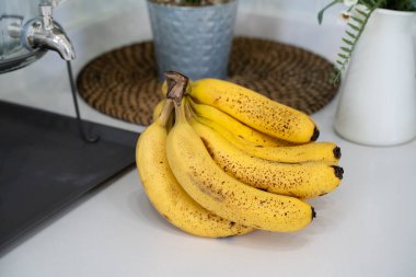 Modern bir mutfakta, sağlıklı bir hayat konseptinde, masada bir demet taze muz yatıyor..