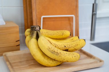 Modern bir mutfakta, sağlıklı bir hayat konseptinde, masada bir demet taze muz yatıyor..