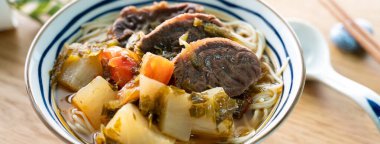 Erişte çorbası. Tayvan 'ın ünlü yemekleri dilimlenmiş kırmızı et ve sebzeler ahşap masa arkasında bir kasede..