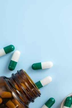 İlaç tasarımı konseptini ele alırsak, kapsül haplarının üst görünümü mavi masa arkasına yayılmış..