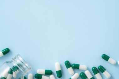 İlaç tasarımı konseptini ele alırsak, kapsül haplarının üst görünümü mavi masa arkasına yayılmış..