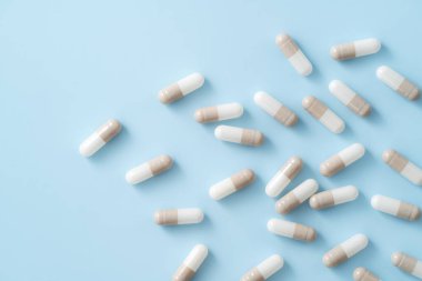 İlaç tasarımı konseptini ele alırsak, kapsül haplarının üst görünümü mavi masa arkasına yayılmış..