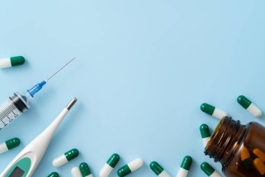 İlaç tasarımı konseptini ele alırsak, kapsül haplarının üst görünümü mavi masa arkasına yayılmış..