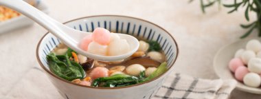 Kırmızı ve beyaz tangyuan, tang yuan, glutinous pirinç köftesi beyaz masa arkasında lezzetli bir çorba ile.