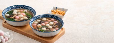 Kırmızı ve beyaz tangyuan, tang yuan, glutinous pirinç köftesi beyaz masa arkasında lezzetli bir çorba ile.