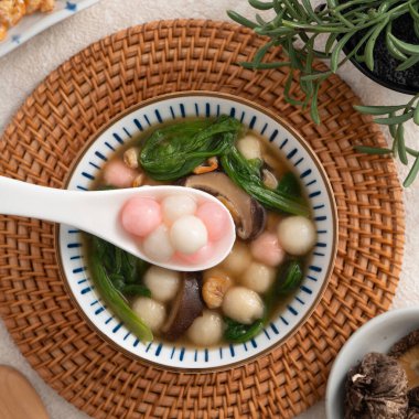 Ev yapımı kırmızı-beyaz tangyuan, tang yuan, glutinous pirinç köftesi ve beyaz arka planda lezzetli bir çorba..