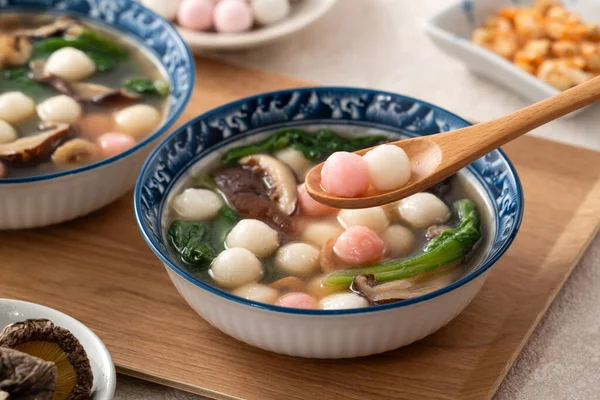 Kırmızı ve beyaz tangyuan, tang yuan, glutinous pirinç köftesi beyaz masa arkasında lezzetli bir çorba ile.