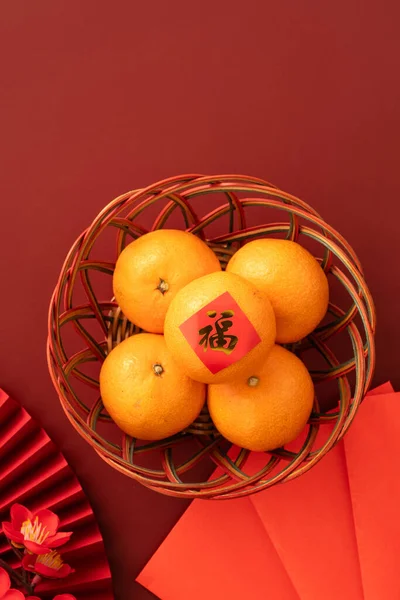 Chinese lunar new year background with fresh tangerine, red envelope, paper fan and decorations for Spring Festival and the word means fortune.