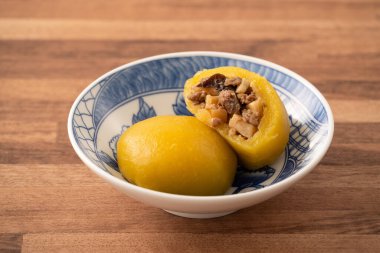 Ev yapımı tatlı patatesli tatlı patates köftesi, domuz eti, mantar ve doğranmış bambu, ahşap masa arkasında bir kasede dolduruluyor..