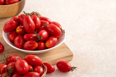 Beyaz masa arkasındaki tabakta taze vişne domatesleri.