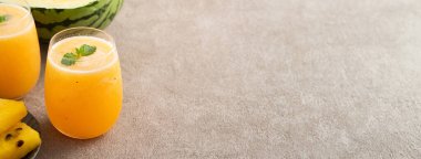 Taze sarı karpuz suyu cam bardakta soğuk içecek ve arka planda dilimlenmiş meyve..