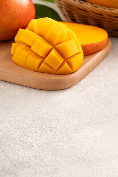 stock image Fresh sliced, cut, diced ripe mango on gray table background with leaf for eating.