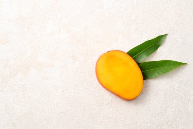 Taze dilimlenmiş, kesilmiş, dilimlenmiş, olgun mango gri masa zemininde yemek için yaprak ile birlikte..