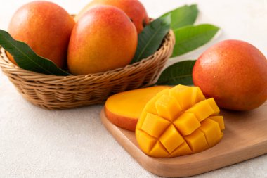 Taze dilimlenmiş, kesilmiş, dilimlenmiş, olgun mango gri masa zemininde yemek için yaprak ile birlikte..