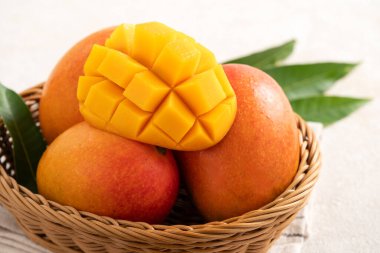 Taze dilimlenmiş, kesilmiş, dilimlenmiş, olgun mango gri masa zemininde yemek için yaprak ile birlikte..