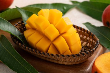 Taze dilimlenmiş, kesilmiş, dilimlenmiş, olgun mango gri masa zemininde yemek için yaprak ile birlikte..