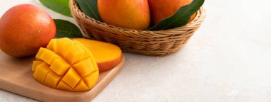 Taze dilimlenmiş, kesilmiş, dilimlenmiş, olgun mango gri masa zemininde yemek için yaprak ile birlikte..