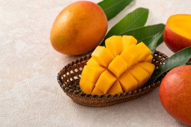 Taze dilimlenmiş, kesilmiş, dilimlenmiş, olgun mango gri masa zemininde yemek için yaprak ile birlikte..