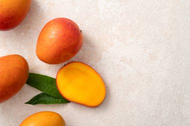 Taze dilimlenmiş, kesilmiş, dilimlenmiş, olgun mango gri masa zemininde yemek için yaprak ile birlikte..
